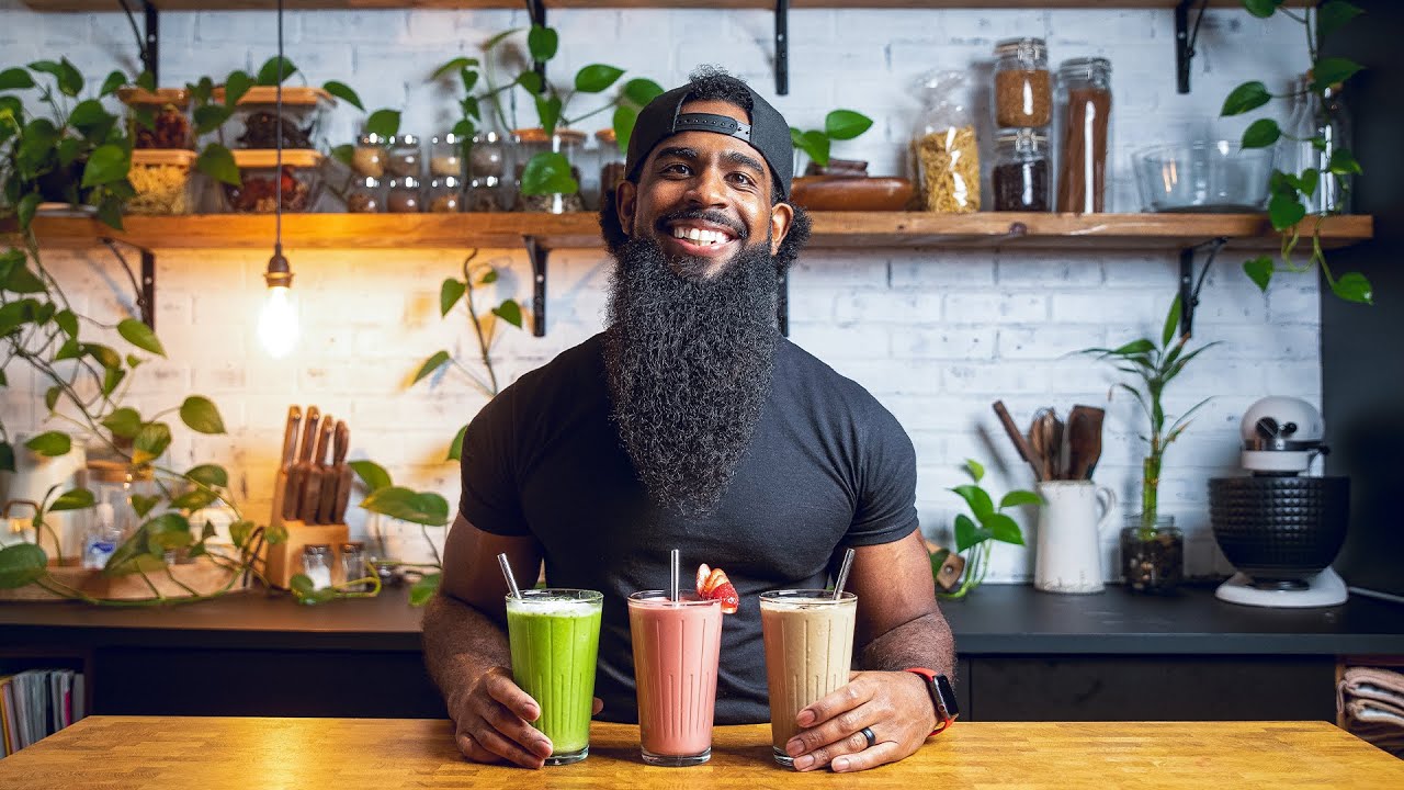 A pink strawberry banana vegan smoothie in a glass with a straw, surrounded by fresh strawberries