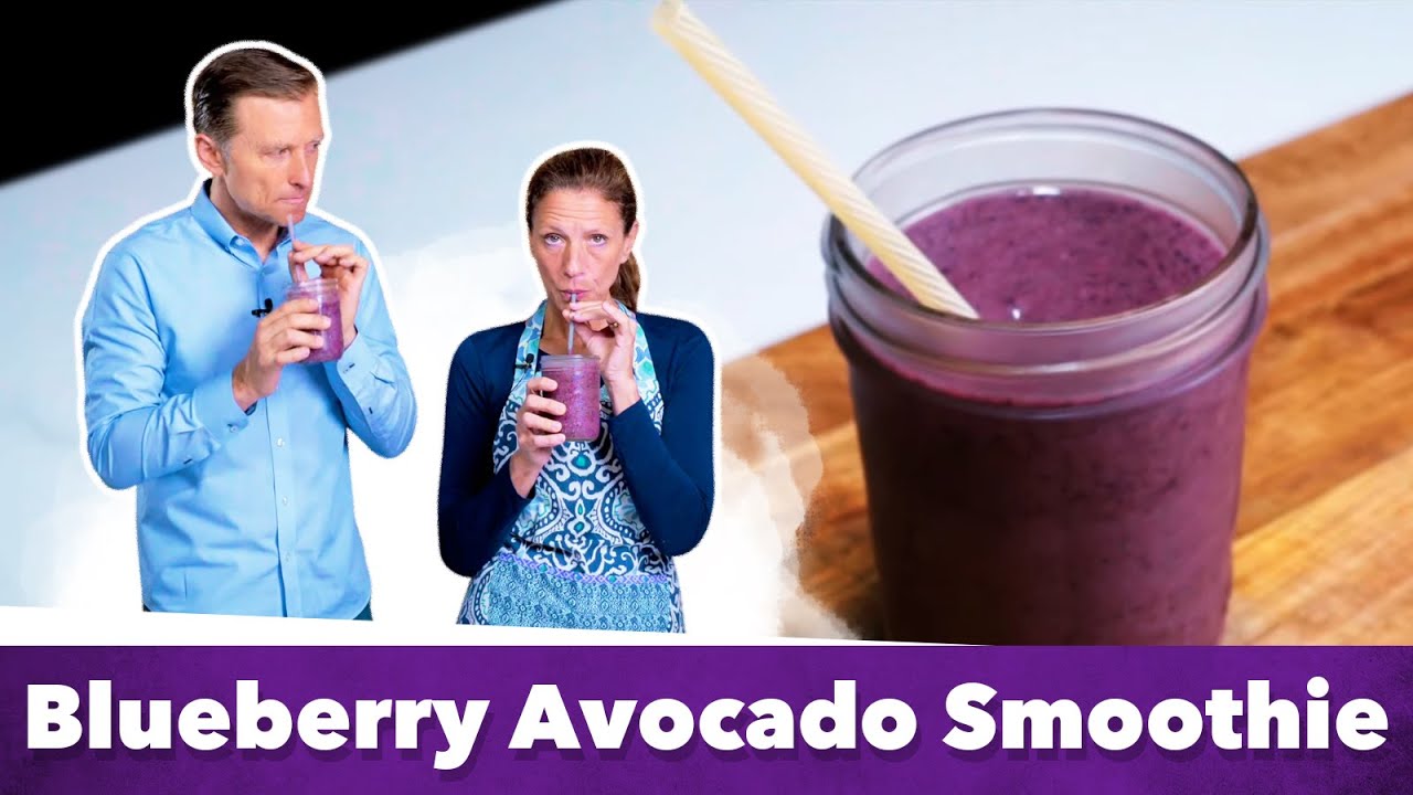 A purple blueberry avocado keto smoothie in a glass on a wooden table