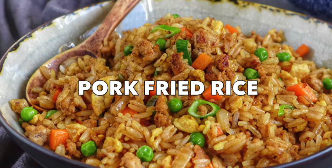 Wok of coconut fried rice with pork tenderloin, egg, scallions, cilantro and lime wedges