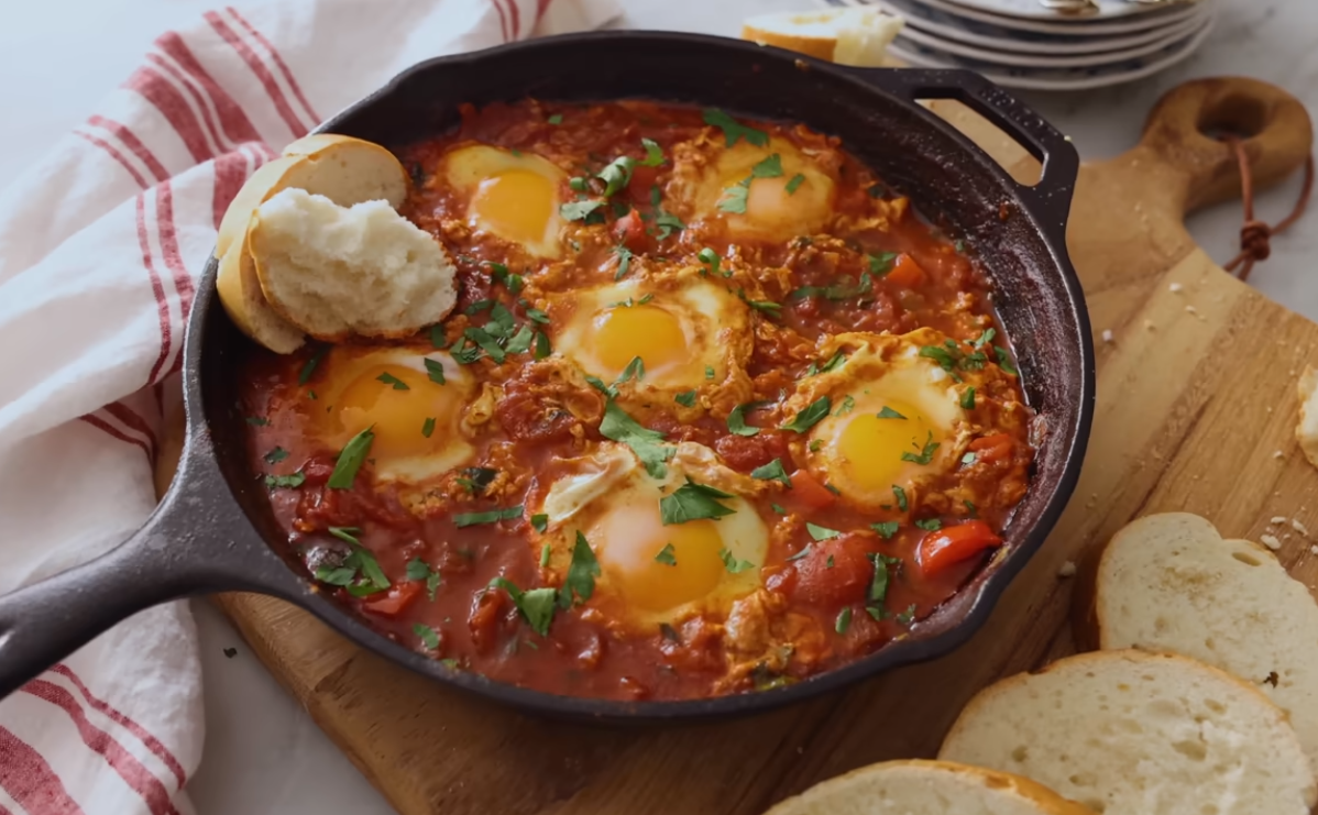 Healthy shakshuka with eggs, feta and fresh herbs in a skillet of thick spiced tomato sauce