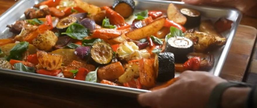 Sheet pan roasted vegetables with eggplant, zucchini, bell peppers, tomatoes and whole garlic cloves, caramelized and garnished with fresh thyme