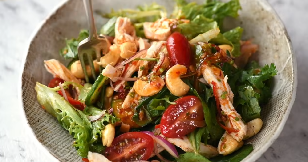Thai minced chicken herbal salad with fresh mint, cilantro, and lime in a white bowl