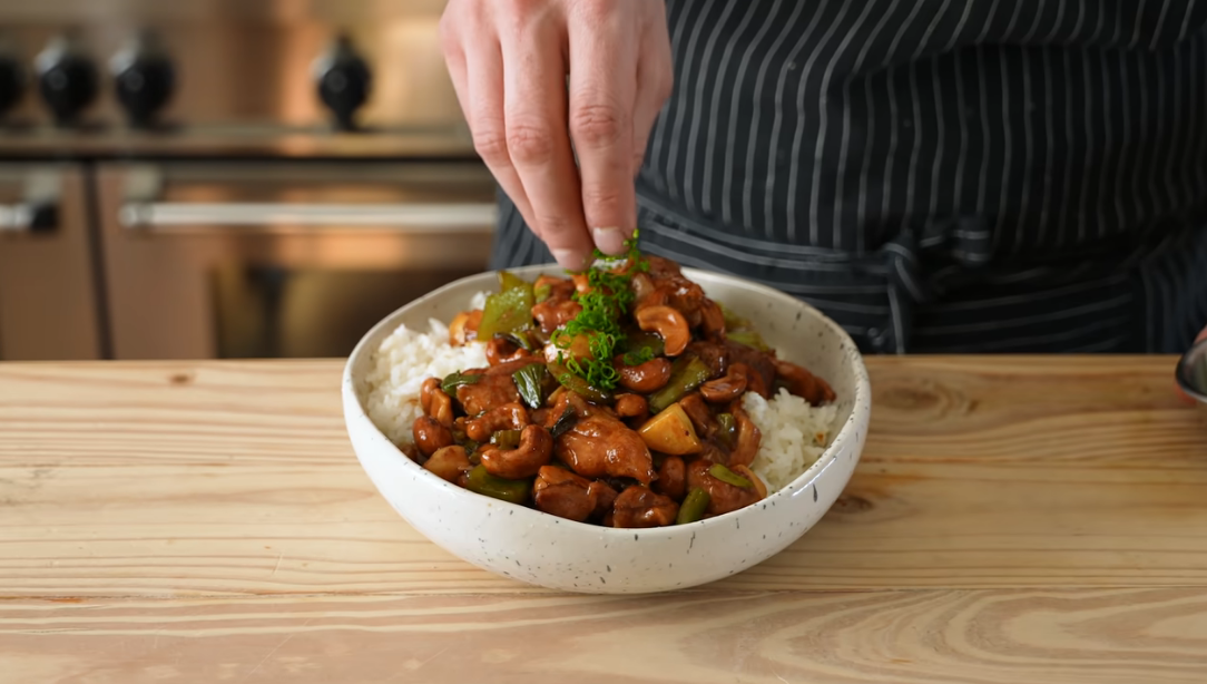 Paleo cashew chicken stir fry with red and green bell peppers and cashews served over cauliflower rice
