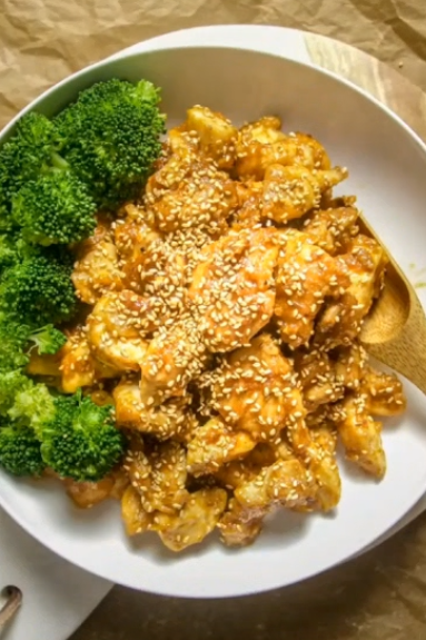 Paleo Chinese New Year sesame chicken glazed with date sauce and sprinkled with sesame seeds, served with steamed broccoli