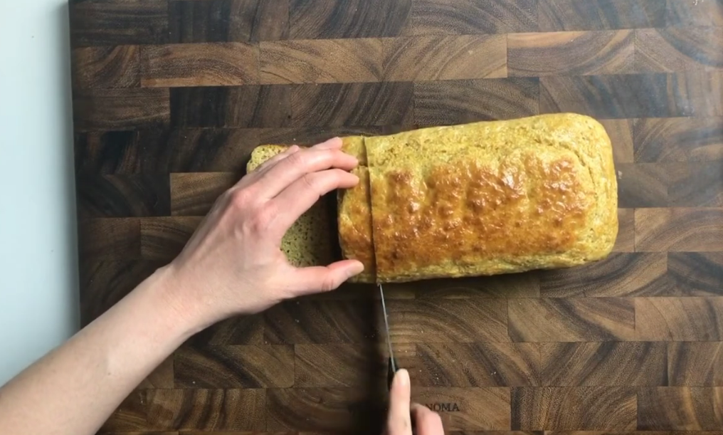 Sliced loaf of homemade paleo sandwich bread with a golden top on a cooling rack